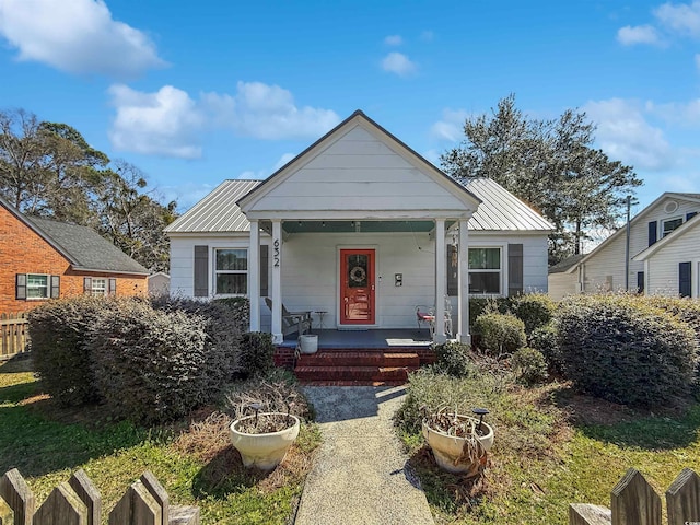 bungalow with metal roof, a porch, and fence