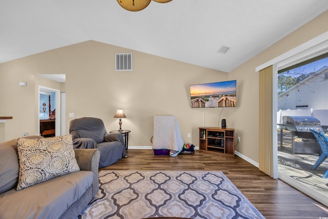 living room with visible vents, wood finished floors, baseboards, and vaulted ceiling