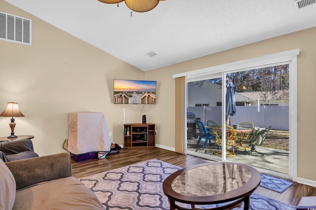 living room featuring visible vents, baseboards, wood finished floors, and vaulted ceiling