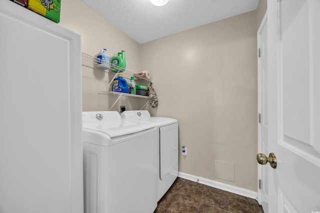 washroom with laundry area, washing machine and dryer, baseboards, and a textured ceiling