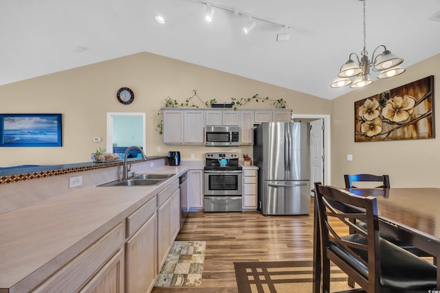 kitchen with light wood-style flooring, a sink, stainless steel appliances, light countertops, and hanging light fixtures