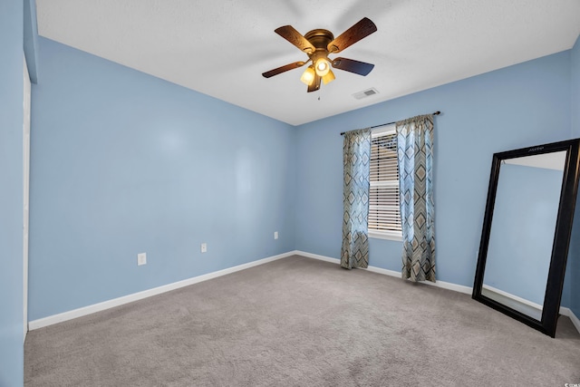 unfurnished room featuring carpet, baseboards, visible vents, and ceiling fan