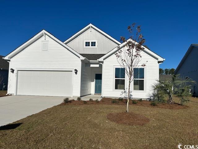 view of front facade with a garage, concrete driveway, a front lawn, and board and batten siding