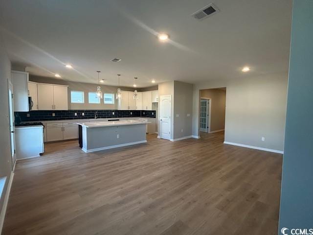 kitchen with white cabinets, dark wood finished floors, visible vents, and decorative backsplash