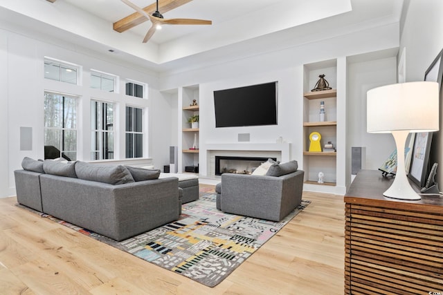 living room featuring ceiling fan, built in shelves, wood finished floors, and a glass covered fireplace