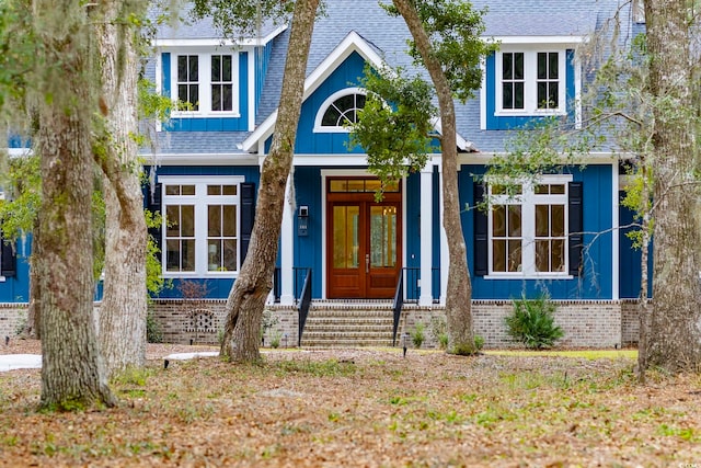 view of front of house with a shingled roof, french doors, brick siding, and board and batten siding