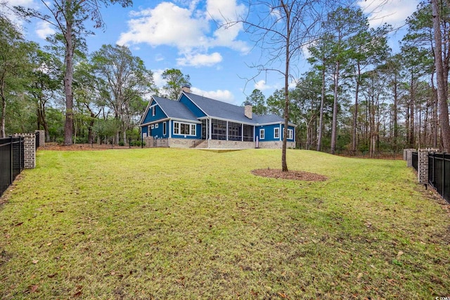 exterior space featuring a yard, a chimney, a fenced backyard, and a sunroom