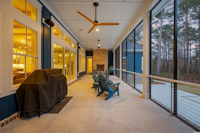 sunroom featuring visible vents, a brick fireplace, and a ceiling fan