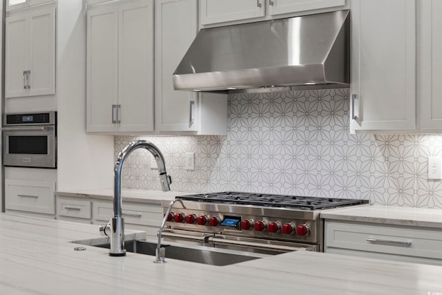 kitchen featuring light stone countertops, oven, decorative backsplash, and exhaust hood