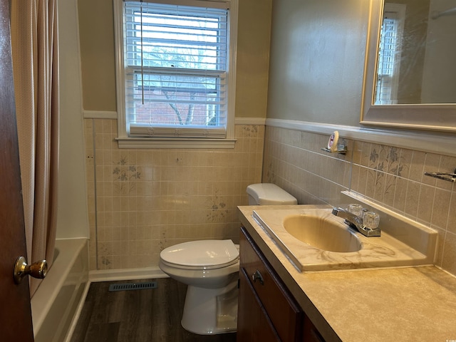 bathroom featuring vanity, wood finished floors, visible vents, shower / bath combination with curtain, and toilet