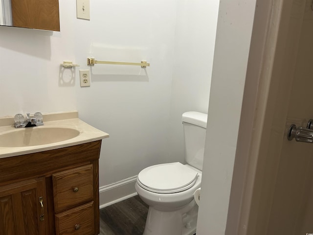 bathroom with baseboards, toilet, wood finished floors, and vanity