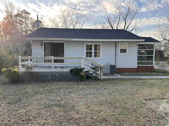 back of house featuring central air condition unit, roof with shingles, a lawn, a chimney, and a deck