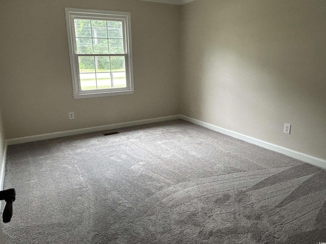 spare room featuring carpet flooring, visible vents, and baseboards