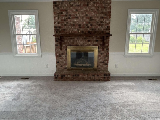 unfurnished living room featuring a wainscoted wall, a fireplace, carpet flooring, and visible vents