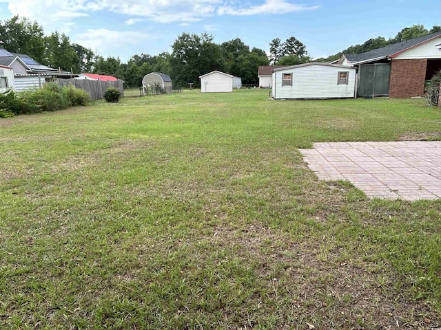 view of yard featuring a patio area, fence, and an outdoor structure