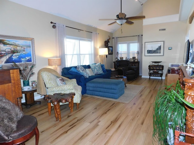 living area featuring a ceiling fan, visible vents, high vaulted ceiling, and light wood-style flooring