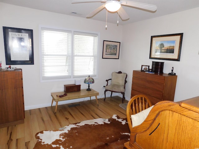 sitting room featuring visible vents, ceiling fan, baseboards, and wood finished floors