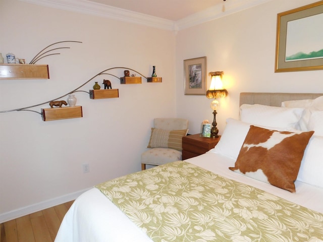 bedroom with crown molding, baseboards, and wood finished floors