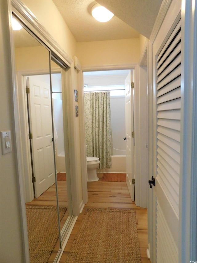 corridor featuring light wood-style flooring and a textured ceiling