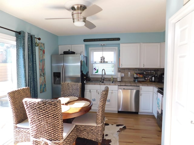 kitchen with white cabinetry, appliances with stainless steel finishes, decorative backsplash, and light wood-style flooring