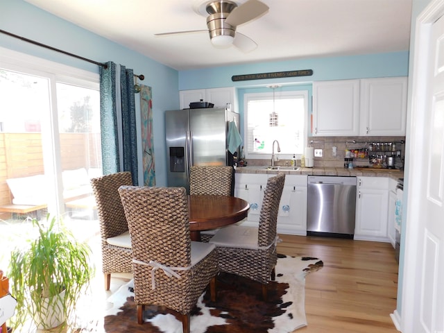 kitchen featuring light wood finished floors, appliances with stainless steel finishes, backsplash, and white cabinets