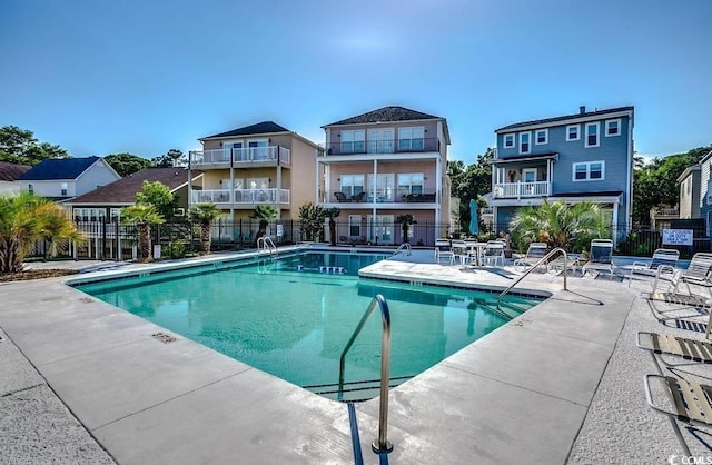 community pool with a patio area and fence