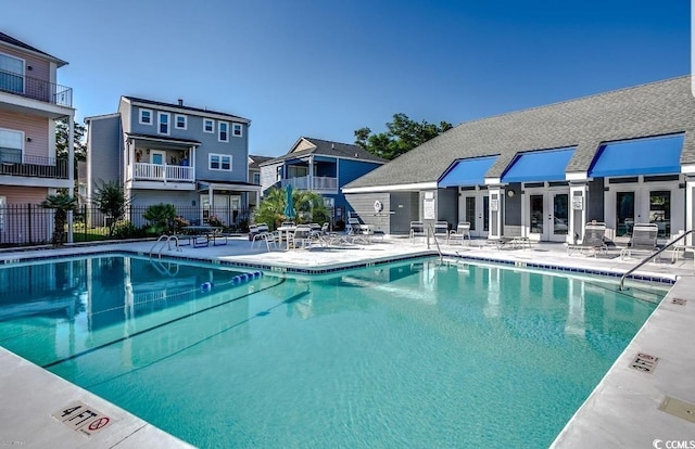 community pool featuring french doors, a patio area, and fence