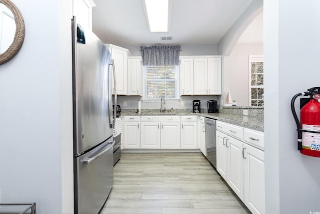 kitchen featuring light wood finished floors, visible vents, stainless steel appliances, white cabinetry, and a sink