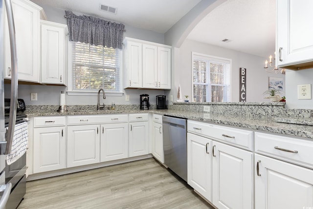 kitchen with a healthy amount of sunlight, white cabinetry, visible vents, and stainless steel dishwasher