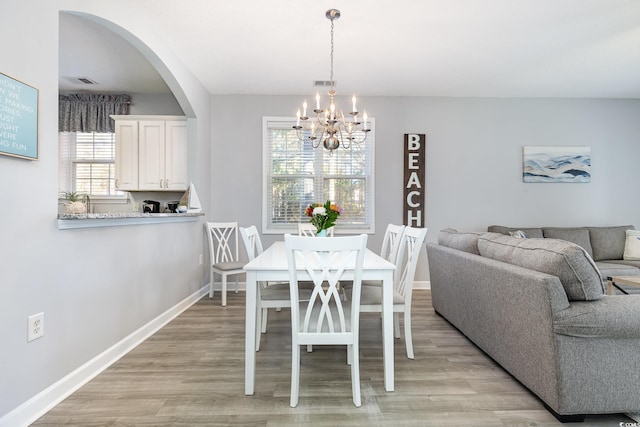 dining area with light wood-style flooring, visible vents, baseboards, and a notable chandelier