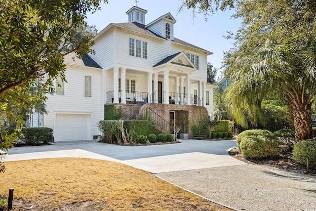 view of front facade with driveway, an attached garage, stairway, and a porch