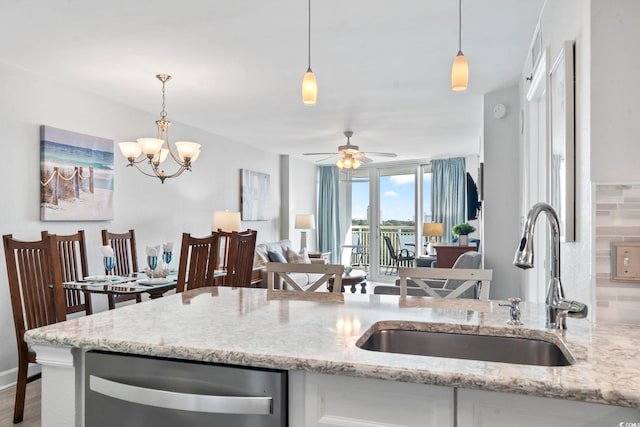 kitchen with decorative light fixtures, white cabinets, a sink, light stone countertops, and dishwasher