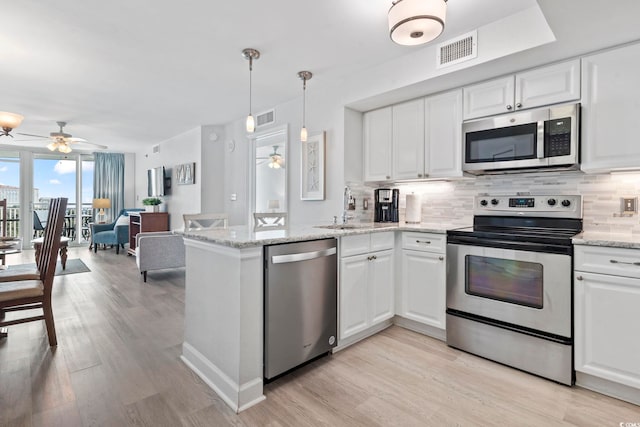 kitchen with visible vents, decorative backsplash, appliances with stainless steel finishes, a peninsula, and a sink