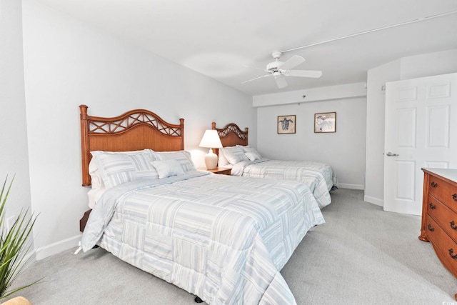 bedroom with light carpet, a ceiling fan, and baseboards