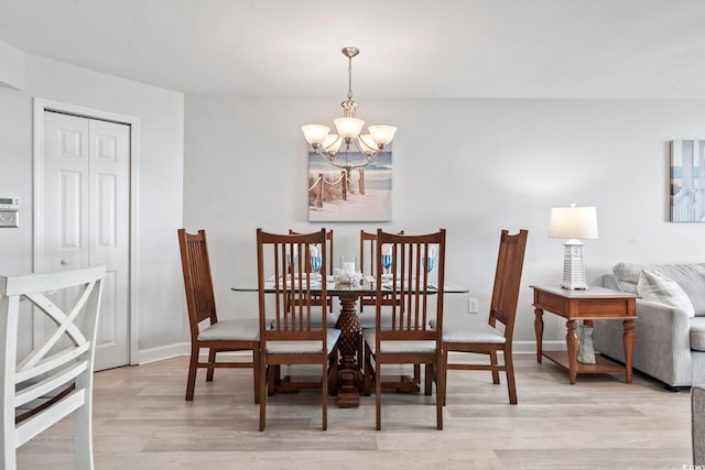 dining area featuring light wood finished floors, baseboards, and a chandelier