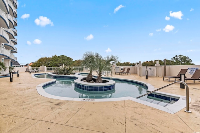 community pool with a patio and a hot tub