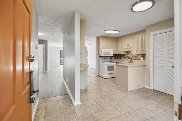 kitchen featuring white appliances, light tile patterned floors, decorative backsplash, light countertops, and a sink