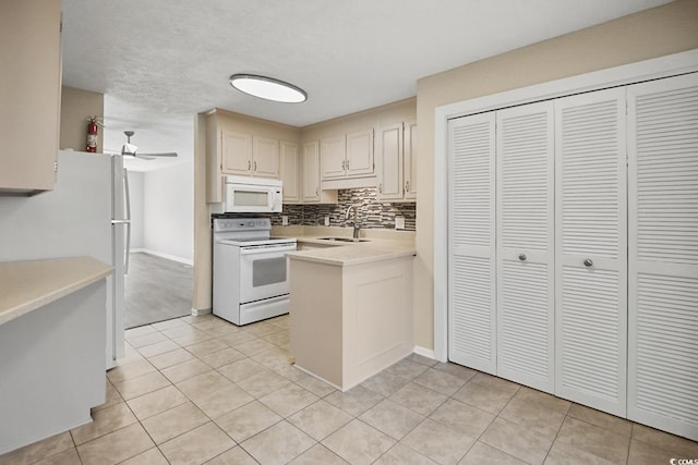 kitchen with white appliances, a peninsula, a sink, light countertops, and backsplash