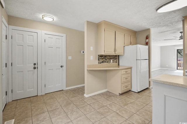 kitchen with light tile patterned floors, light countertops, decorative backsplash, freestanding refrigerator, and ceiling fan