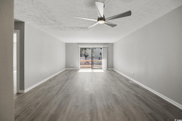 empty room featuring a textured ceiling, ceiling fan, dark wood finished floors, and baseboards