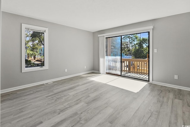 unfurnished room featuring visible vents, baseboards, and wood finished floors