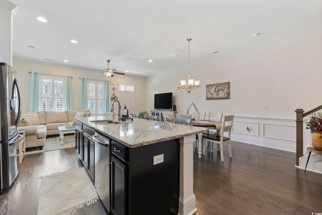 kitchen with dark cabinets, appliances with stainless steel finishes, open floor plan, and a sink