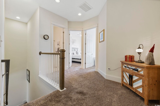 corridor featuring baseboards, visible vents, an upstairs landing, carpet floors, and recessed lighting