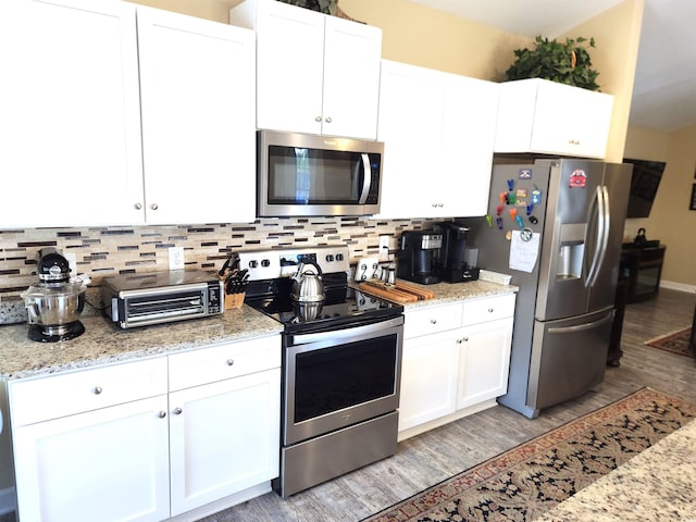 kitchen featuring appliances with stainless steel finishes, light wood-style flooring, backsplash, and white cabinetry