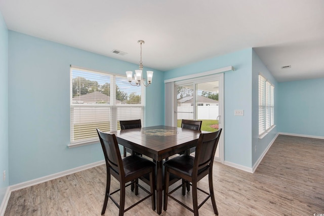 dining space featuring a chandelier, light wood-type flooring, visible vents, and baseboards