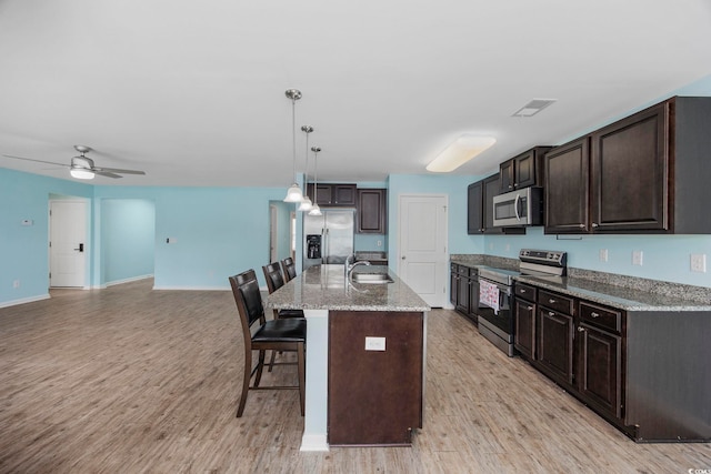 kitchen featuring visible vents, appliances with stainless steel finishes, a sink, light wood-type flooring, and a kitchen breakfast bar