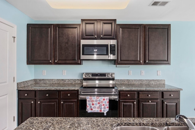 kitchen with dark brown cabinetry, visible vents, appliances with stainless steel finishes, and a sink