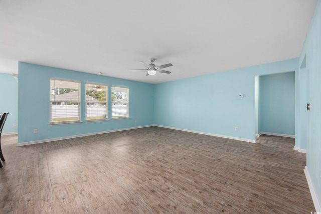 unfurnished living room with ceiling fan, wood finished floors, and baseboards