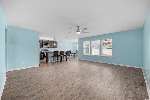 living area with a ceiling fan, baseboards, and wood finished floors