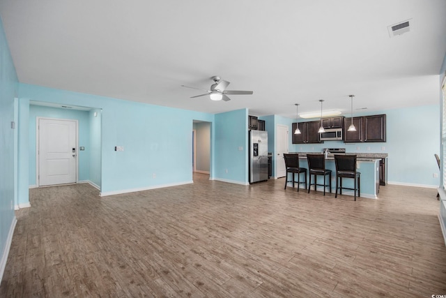 unfurnished living room featuring ceiling fan, baseboards, visible vents, and light wood-style floors